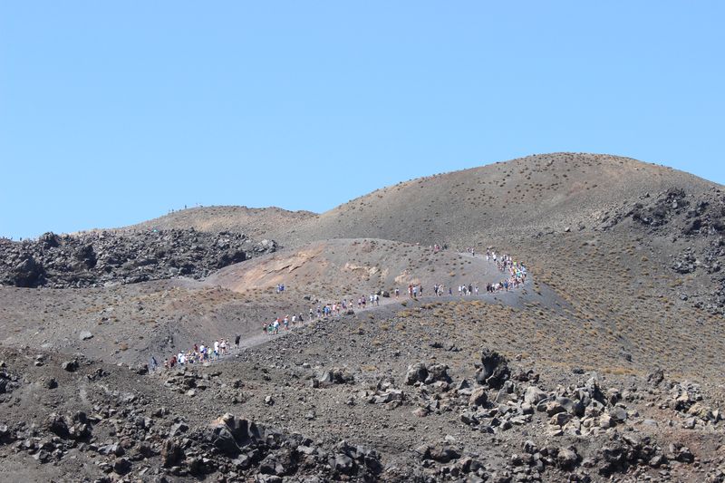 Line of tourists crawling along the bald mountain. Such an extraterrestrial scenery! Nea Kameni island, Santorini